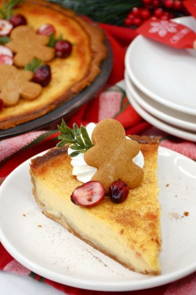 eggnog custard pie served on a white plate, with the remaining pie in the background along with a stack of serving plates