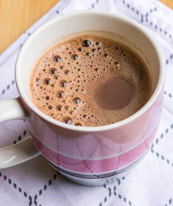 a pink striped mug of hot chocolate made with chocolate chips