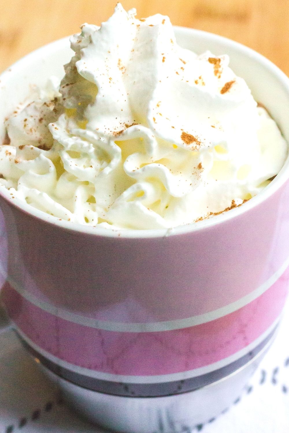 paris-style hot chocolate topped with whipped cream, served in a pink striped mug