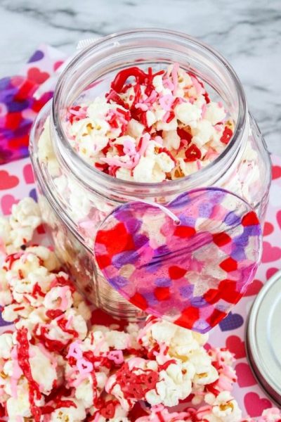 valentines day sweetheart popcorn in a jar, with more popcorn scattered around it