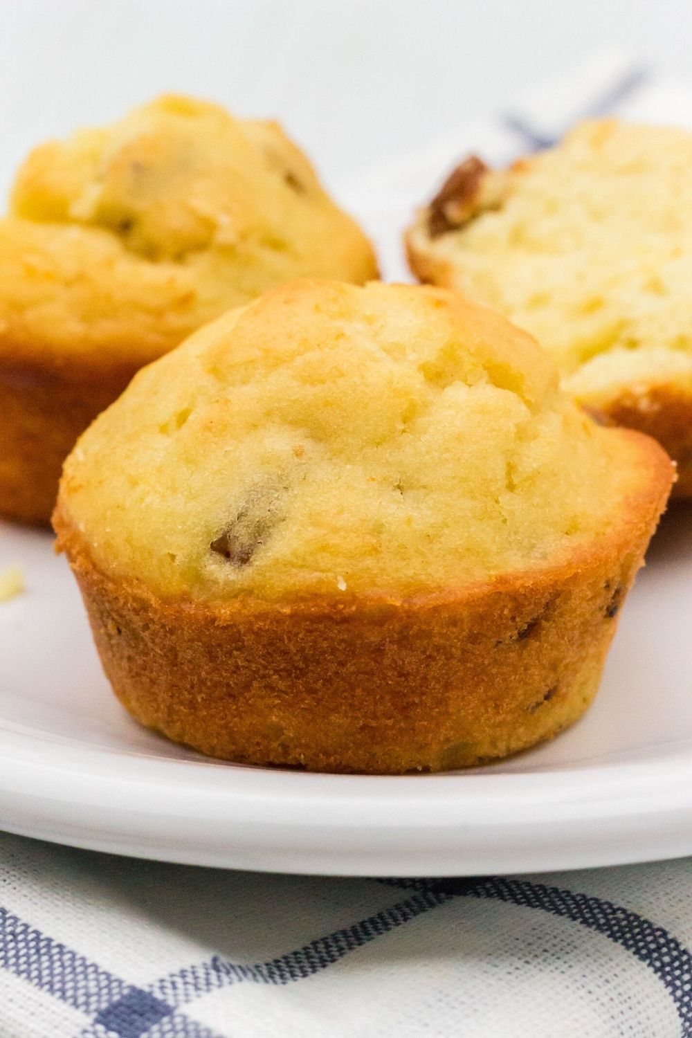 three whole German-style muffins on a plate, with one muffin close-up in the center of the photo.