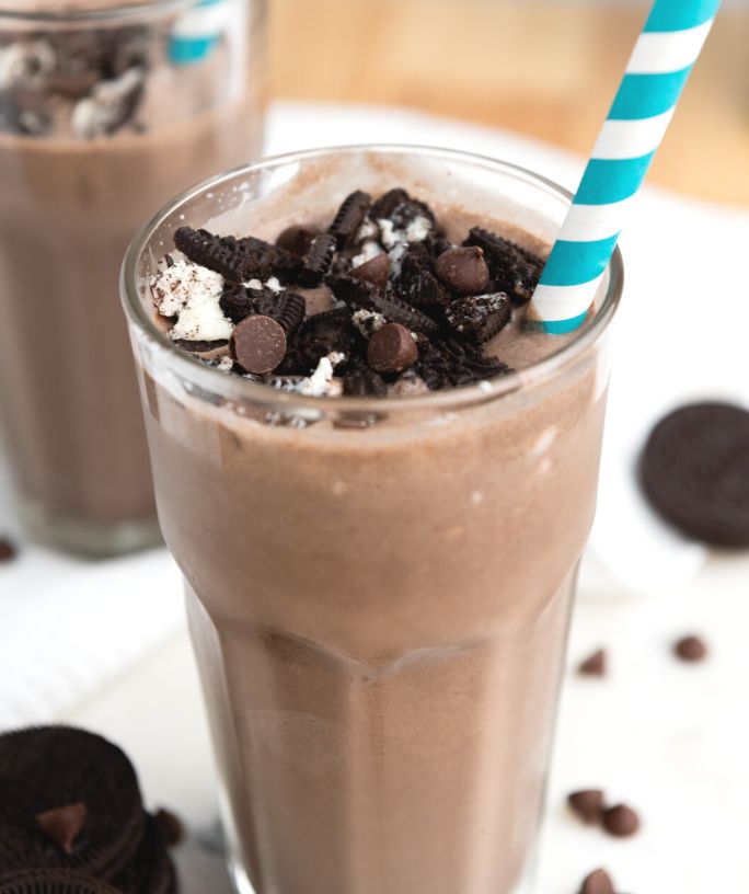 Oreo milkshake made without ice cream, served in a pint glass, garnished with Oreo chunks and served with a straw