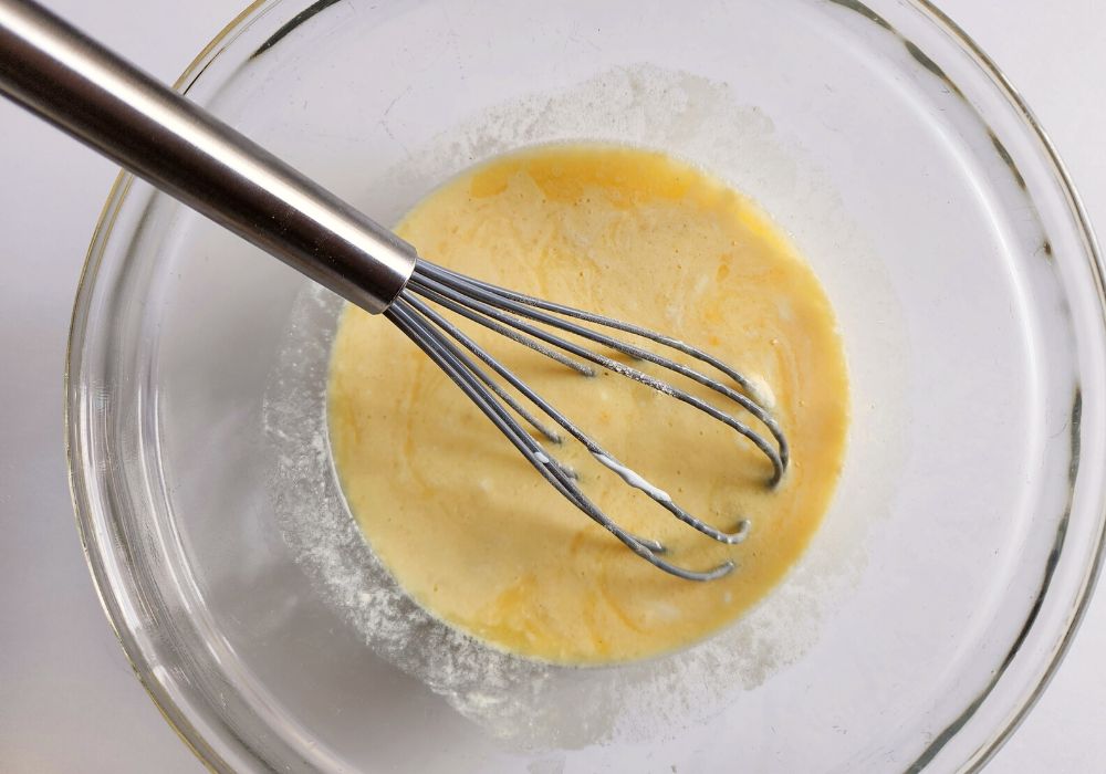 eggs, butter, and sour cream whisked together in a mixing bowl