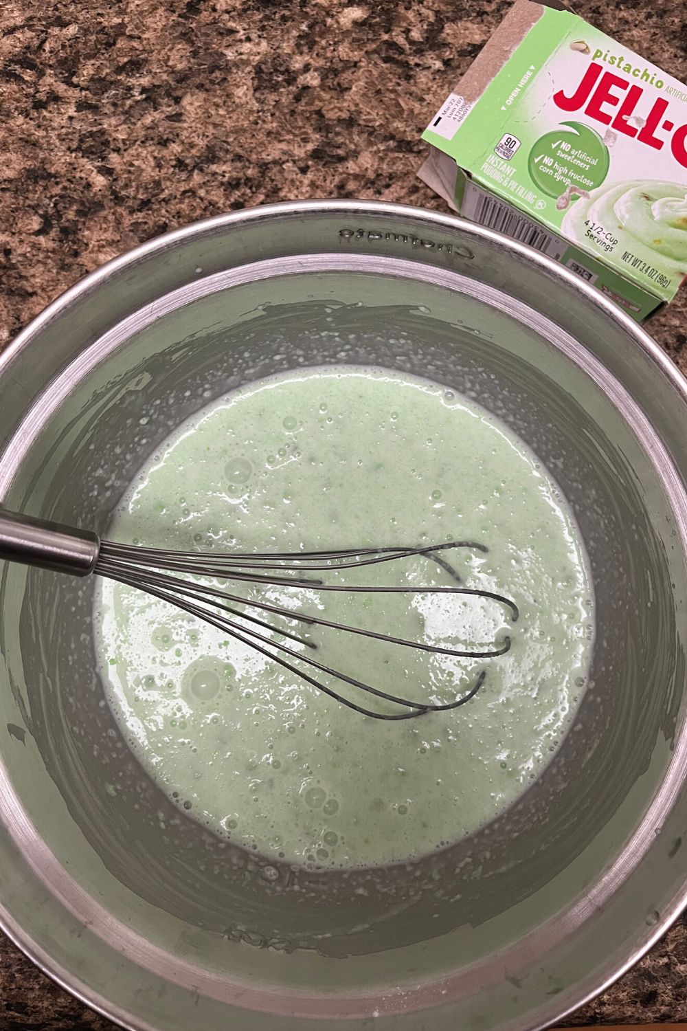 pistachio pudding mix being dissolved in milk and heavy whipping cream