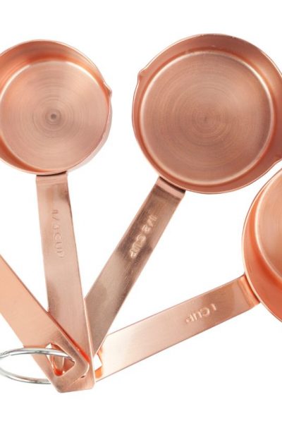 a set of copper measuring cups splayed out, displaying the markings on each