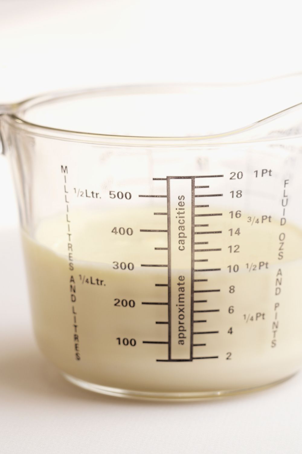 glass liquid measuring cup with milk in it