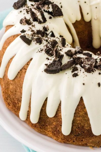 Edge of an Oreo pound cake baked in a bundt pan, drizzled with cream cheese icing and topped with crushed Oreos