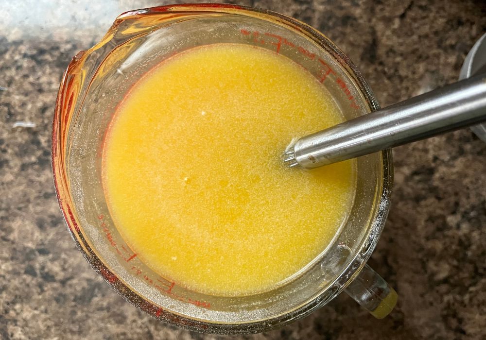 Dole Whip Soft Serve Mix dissolved in water in a glass measuring cup with a whisk