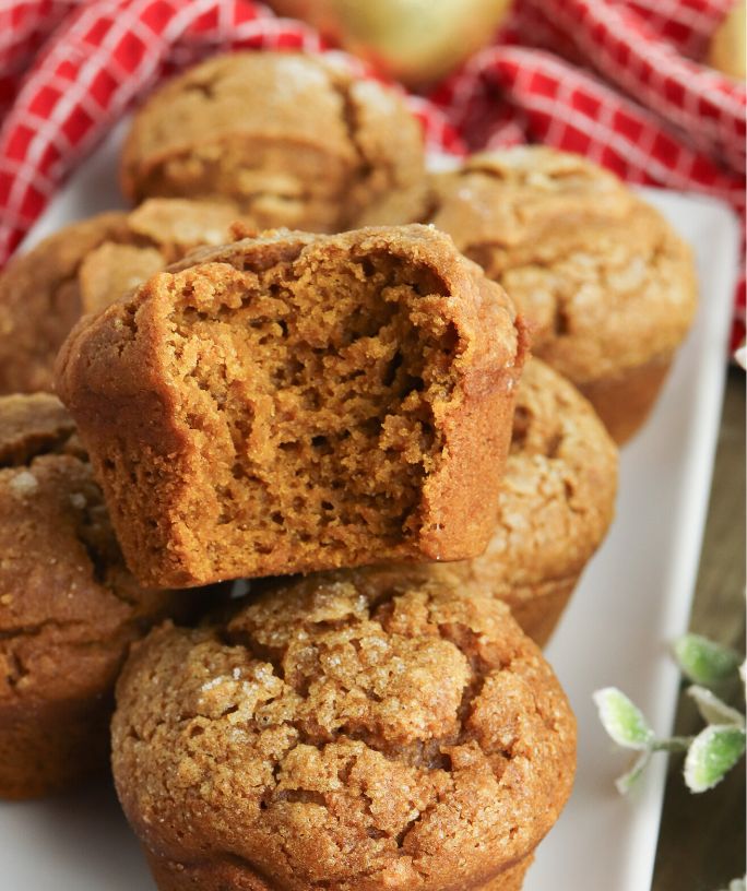 a few pumpkin gingerbread muffins, one of which has a bite taken out of it, showing the moist interior