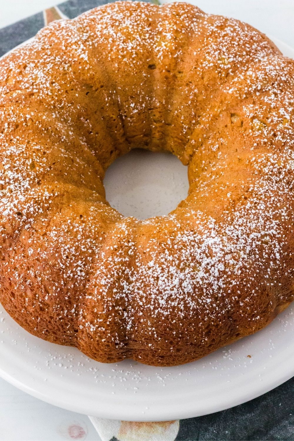 overhead view of a sweet potato bundt cake dusted with powdered sugar and displayed on a white plate